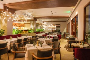 Un restaurante con varias mesas, sillas y una zona de bar.