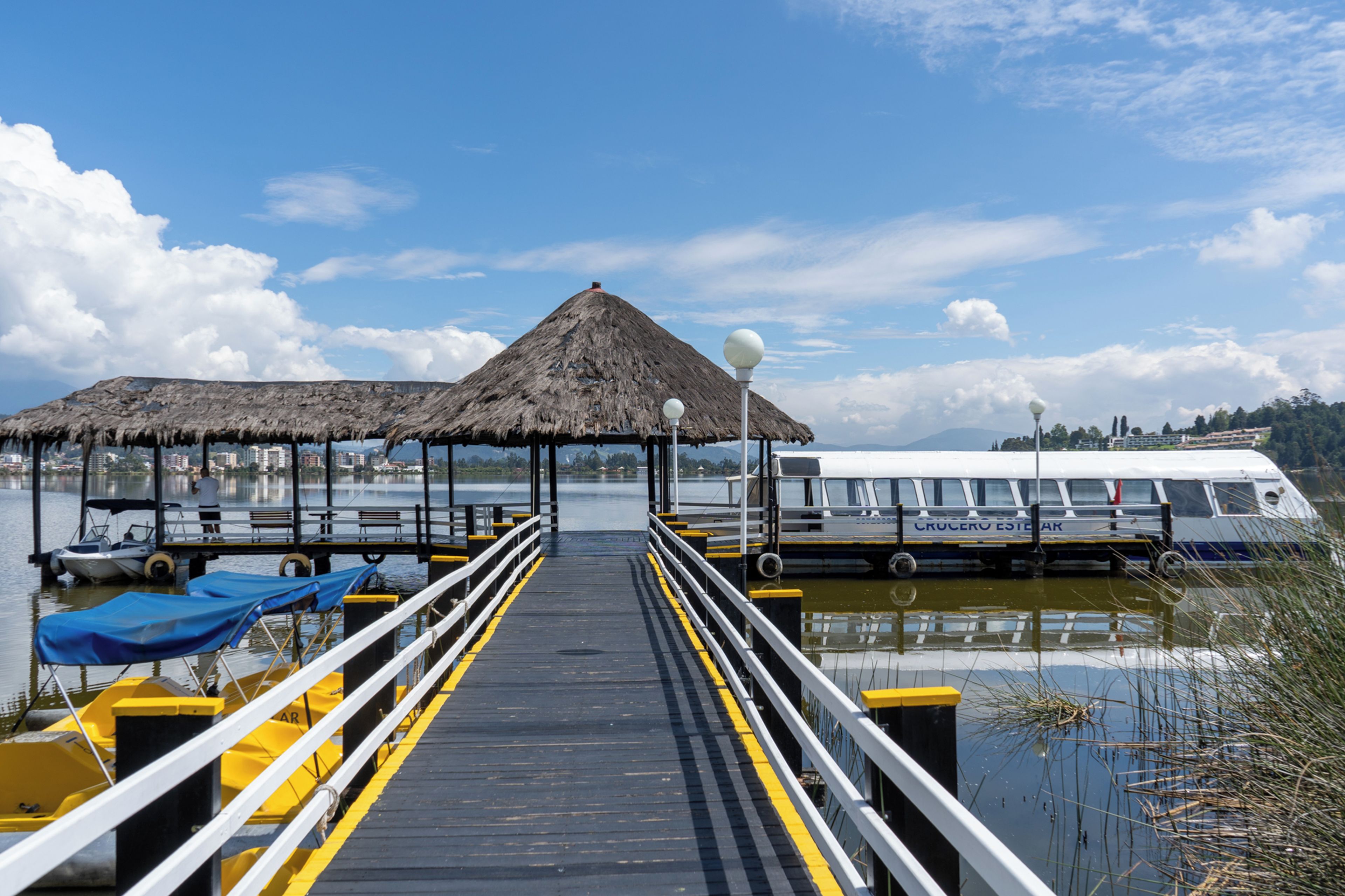 A pier leading to a thatched-roof structure with a boat docked nearby.