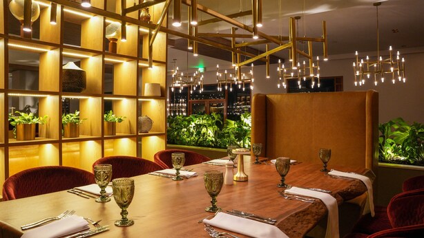 A restaurant with a long wooden table set for dining, red upholstered chairs, and a warm ambient lighting. - Estelar Paipa Hotel Spa & Centro de Convenciones (Paipa)
