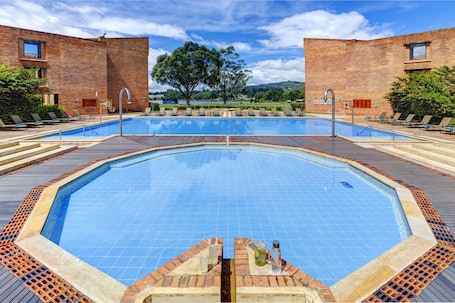 Una piscina al aire libre, sombrillas, sillones reclinables de piscina