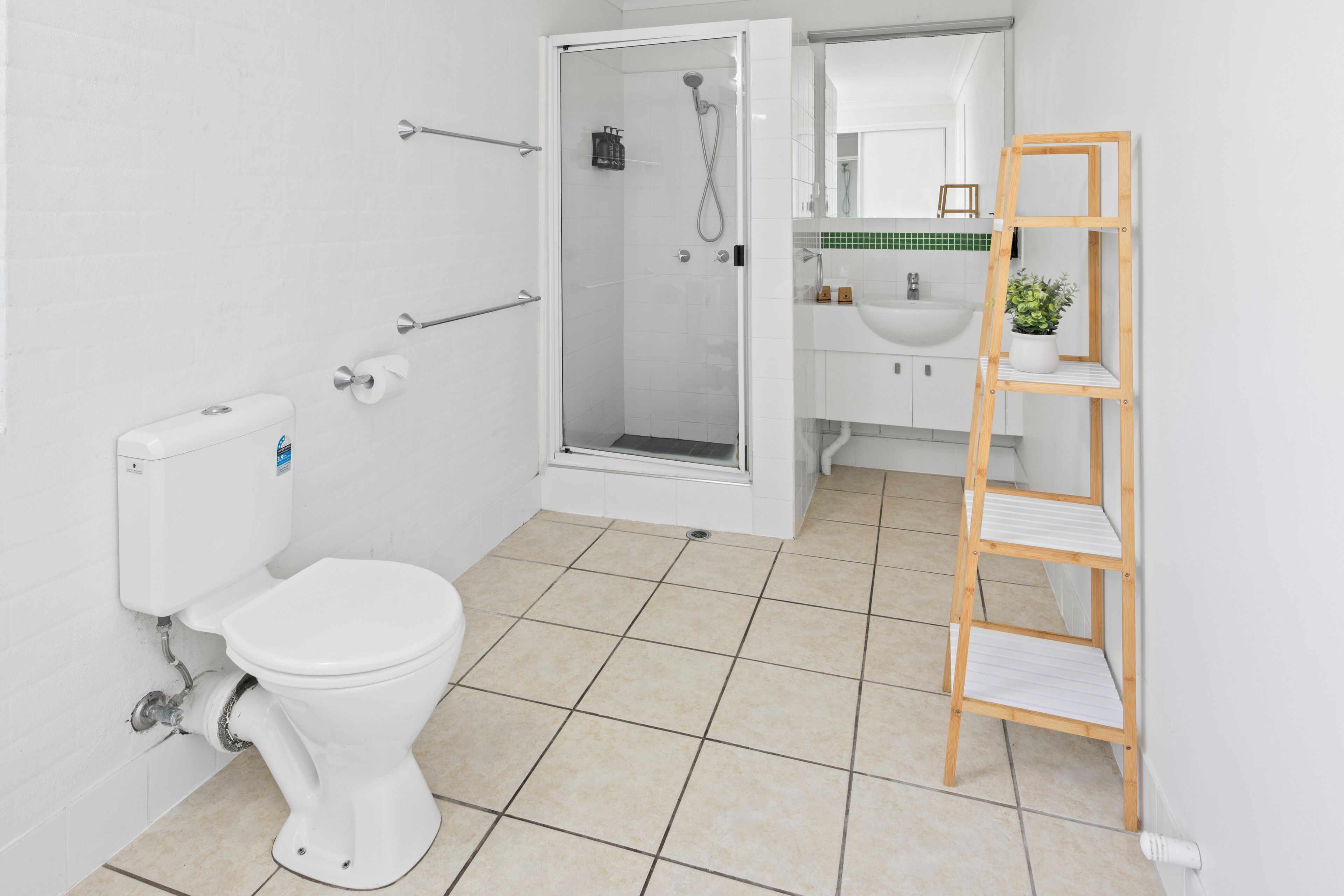 A modern bathroom with a toilet, shower, and sink.