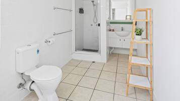 A modern bathroom with a toilet, shower, and sink.
