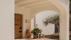 A courtyard with a wooden door, terracotta pots, and a potted plant under a white archway. - Hotel Rural Sant Ignasi (Ciutadella de Menorca)