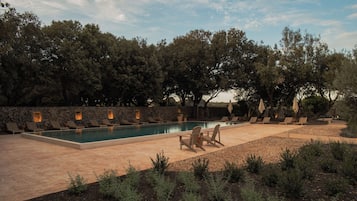 Una piscina al aire libre, sombrillas, sillones reclinables de piscina