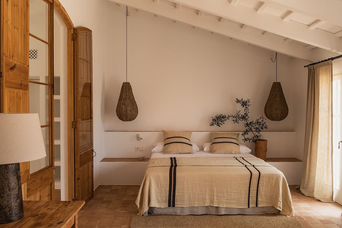 A bedroom with a bed, wooden wardrobe, and hanging lamps.