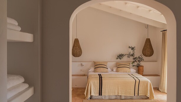 A bedroom with a bed, hanging lamps, and a plant. - Hotel Rural Sant Ignasi (Ciutadella de Menorca)