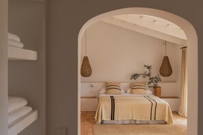 A bedroom with a bed, hanging lamps, and a plant.