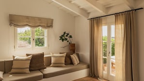 A cozy room with a built-in bench, a window with a valance, a potted plant, and a view through a glass door. - Hotel Rural Sant Ignasi (Ciutadella de Menorca)