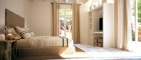 Une chambre à coucher avec un lit, une table de chevet, une lampe et une vue sur l’extérieur.
