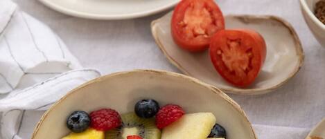 Une table mise pour le petit-déjeuner avec un bol de fruits, une assiette de toasts et un petit pot de confiture.