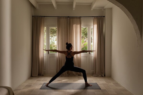 A person in a yoga pose on a mat in a room with a door and curtains.