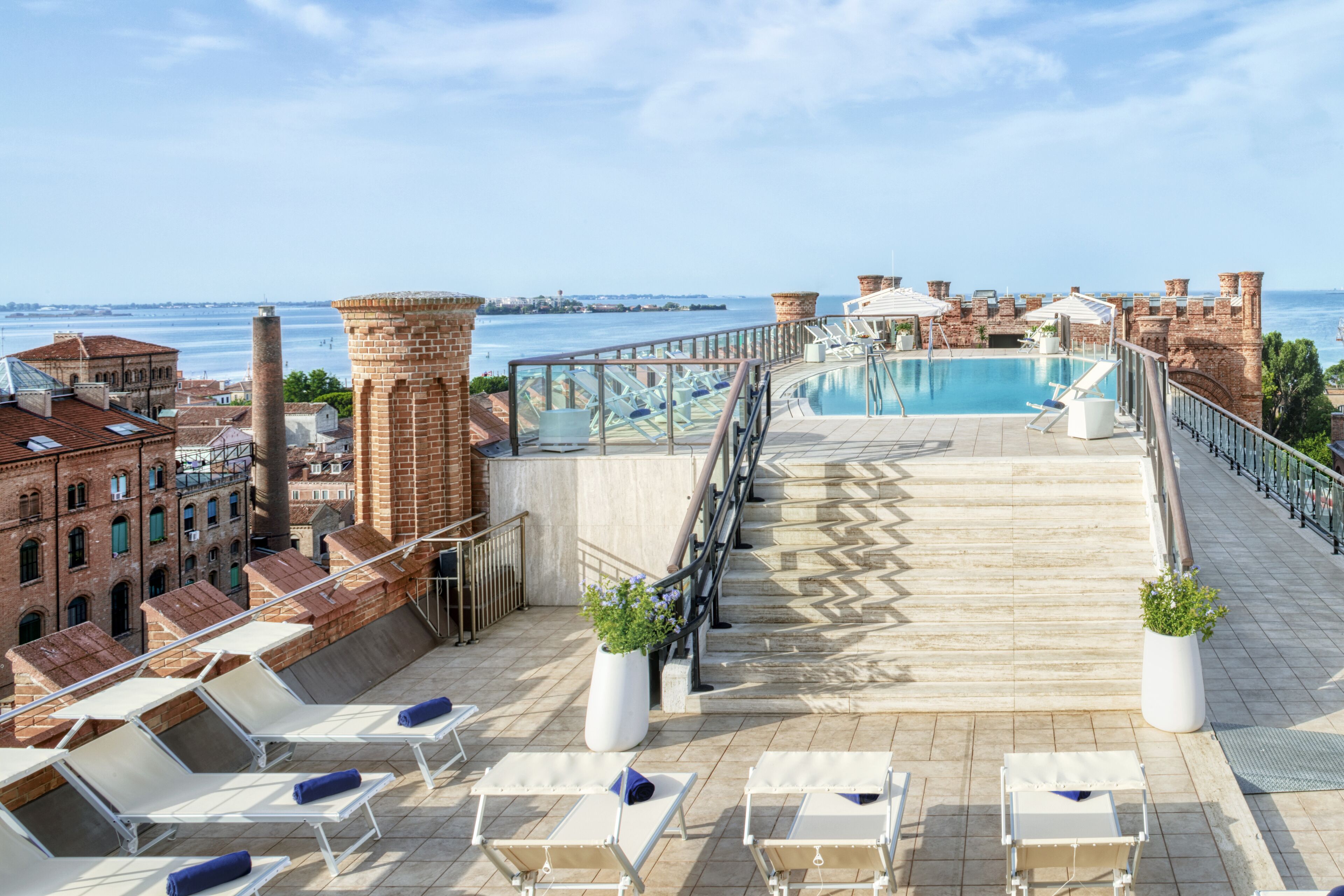Un área de piscina en la azotea con sillones de descanso y vistas al mar.