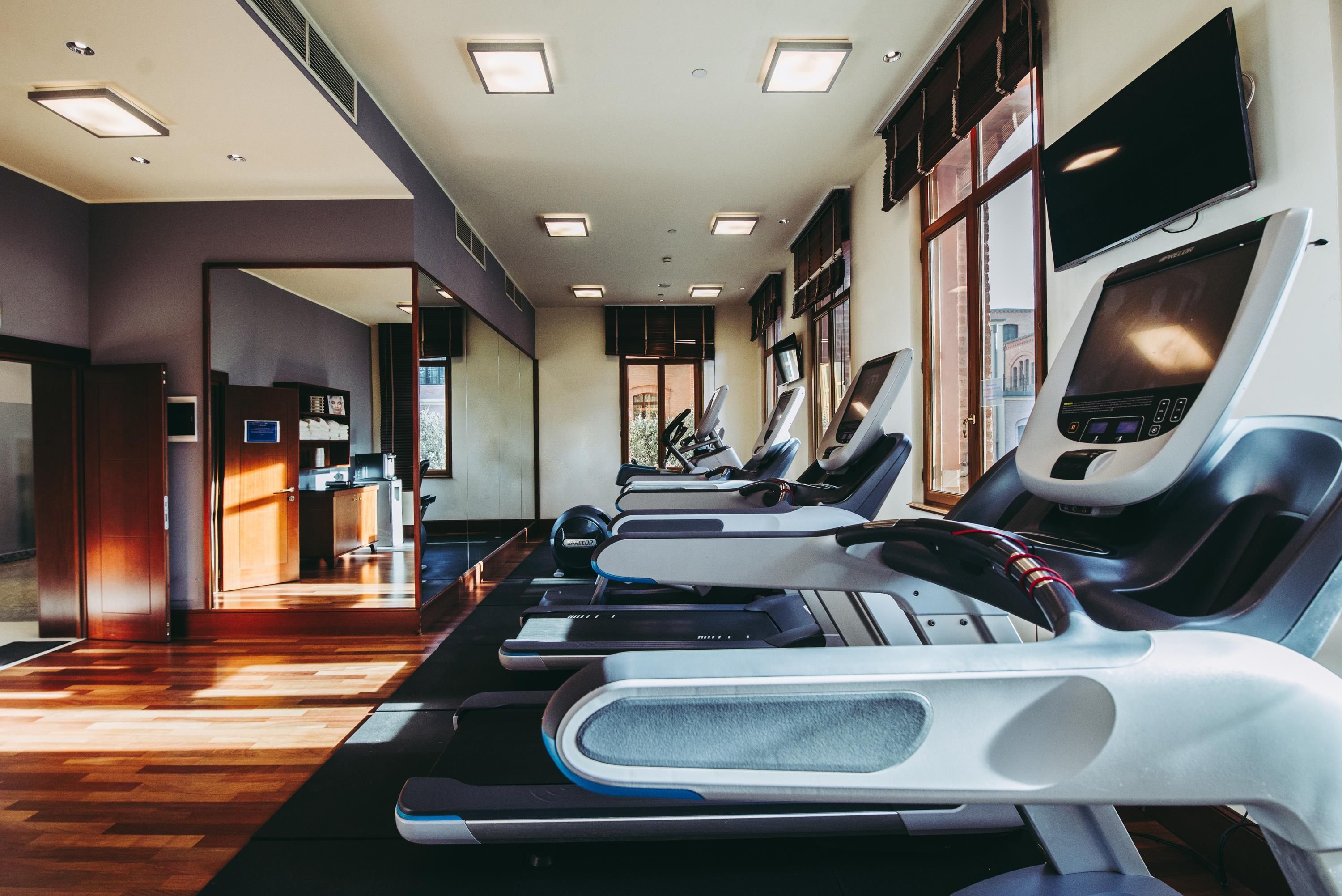 Una palestra con diverse tapis roulant, un'area reception e ampie finestre.