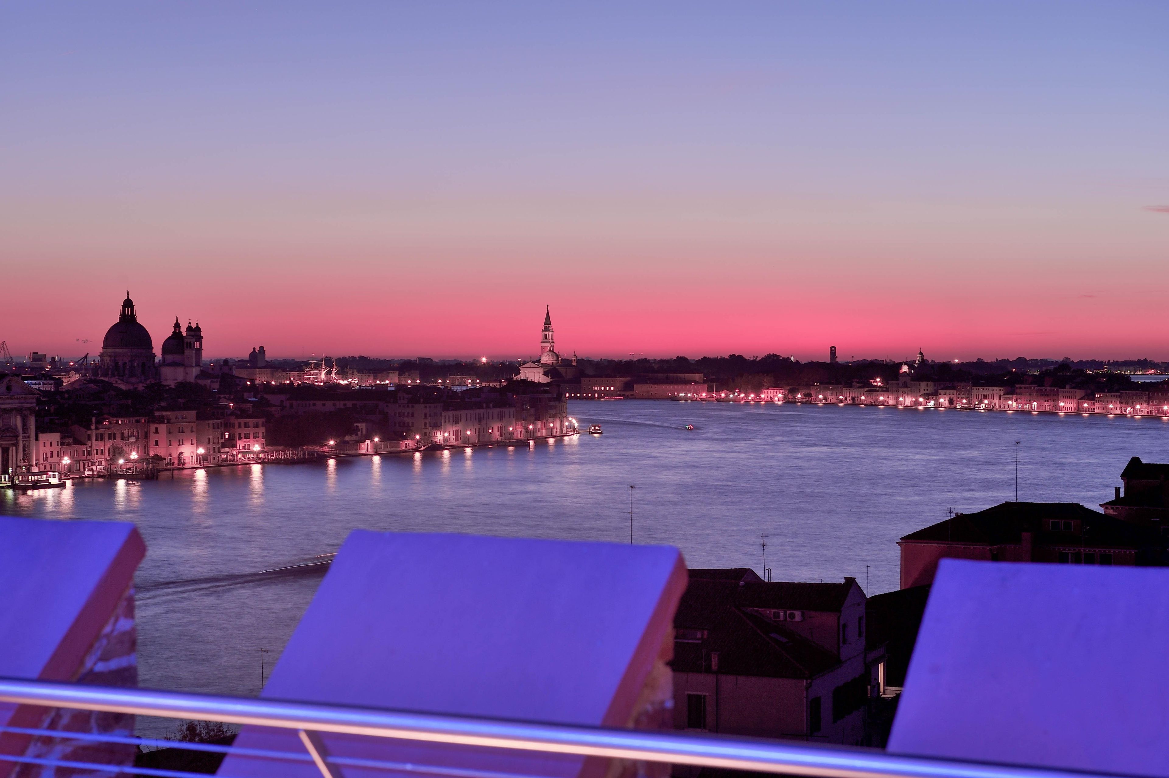Une vue d’une ville au crépuscule, avec une rivière, des bâtiments et un pont.