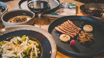 A table with various dishes, including grilled meat, vegetables, and a bowl of beans.