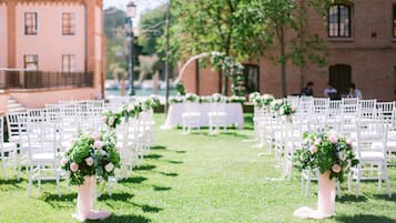 En vielsesgang med hvide stole og blomsterarrangementer.