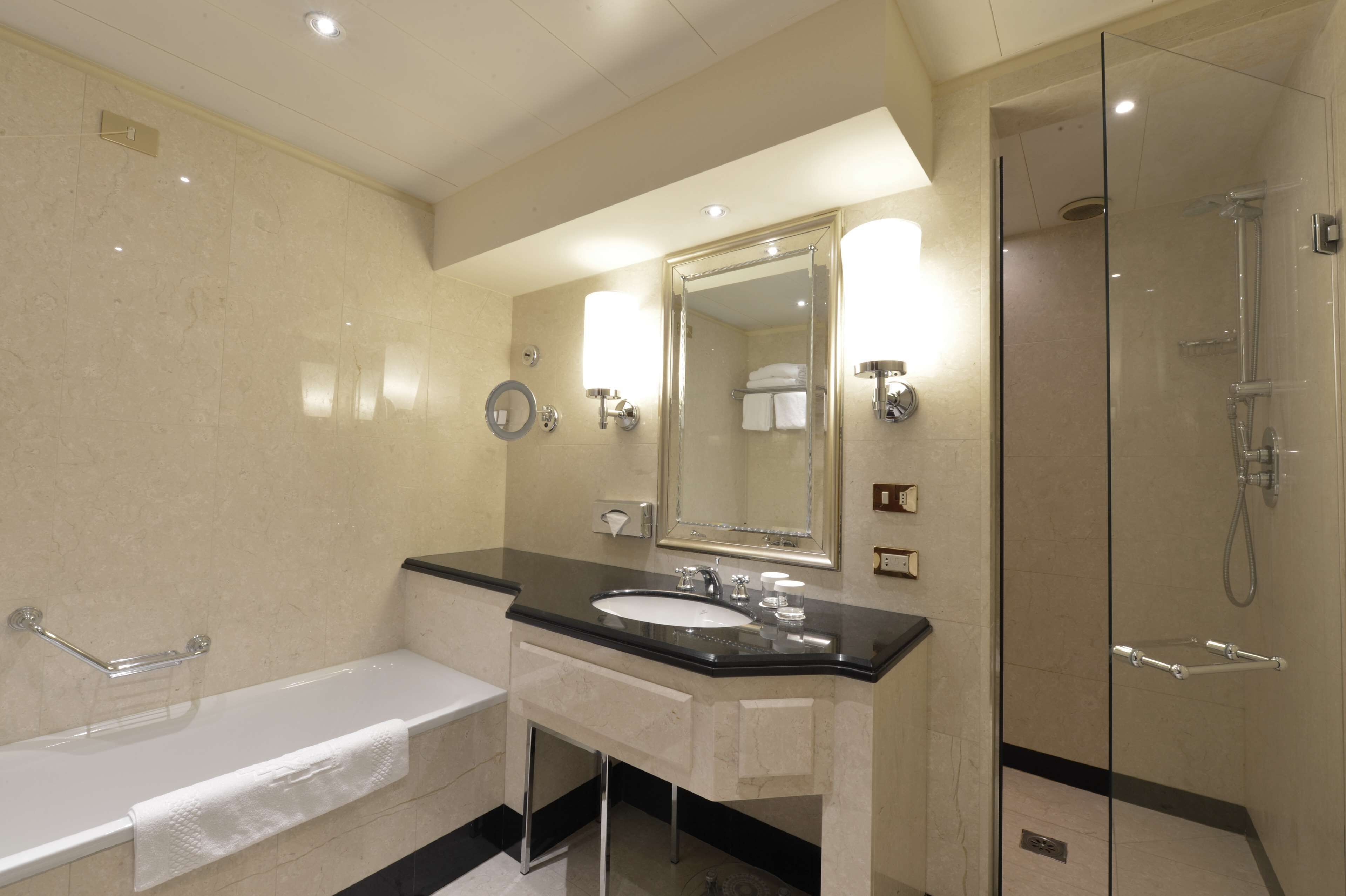 A modern bathroom with a bathtub, sink, and glass-enclosed shower.