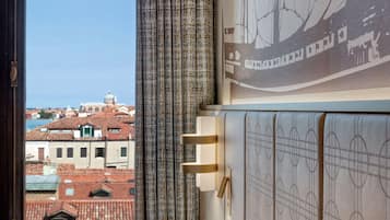 A room with a view of a cityscape, a patterned curtain, and a wall-mounted light fixture.