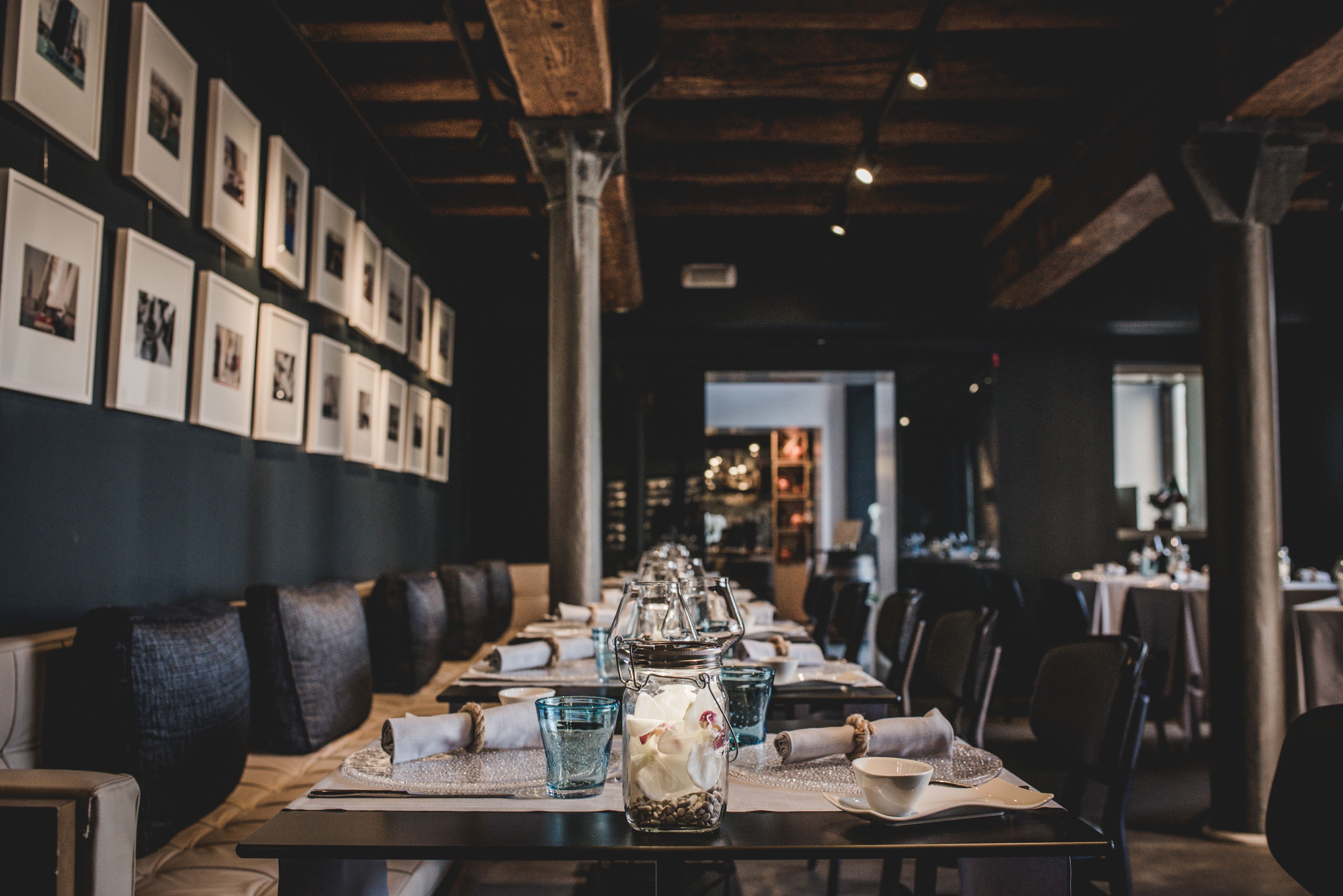 Un restaurante con una larga mesa lista para comer, cuadros en la pared y un techo de madera rústica.