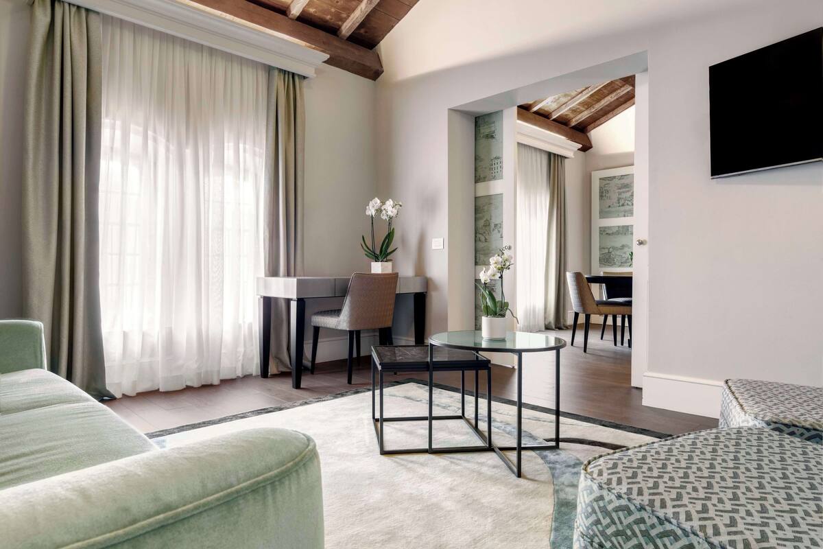 Un salon moderne avec un canapé, une table en verre et un fauteuil. On peut voir une plante en pot sur la table.