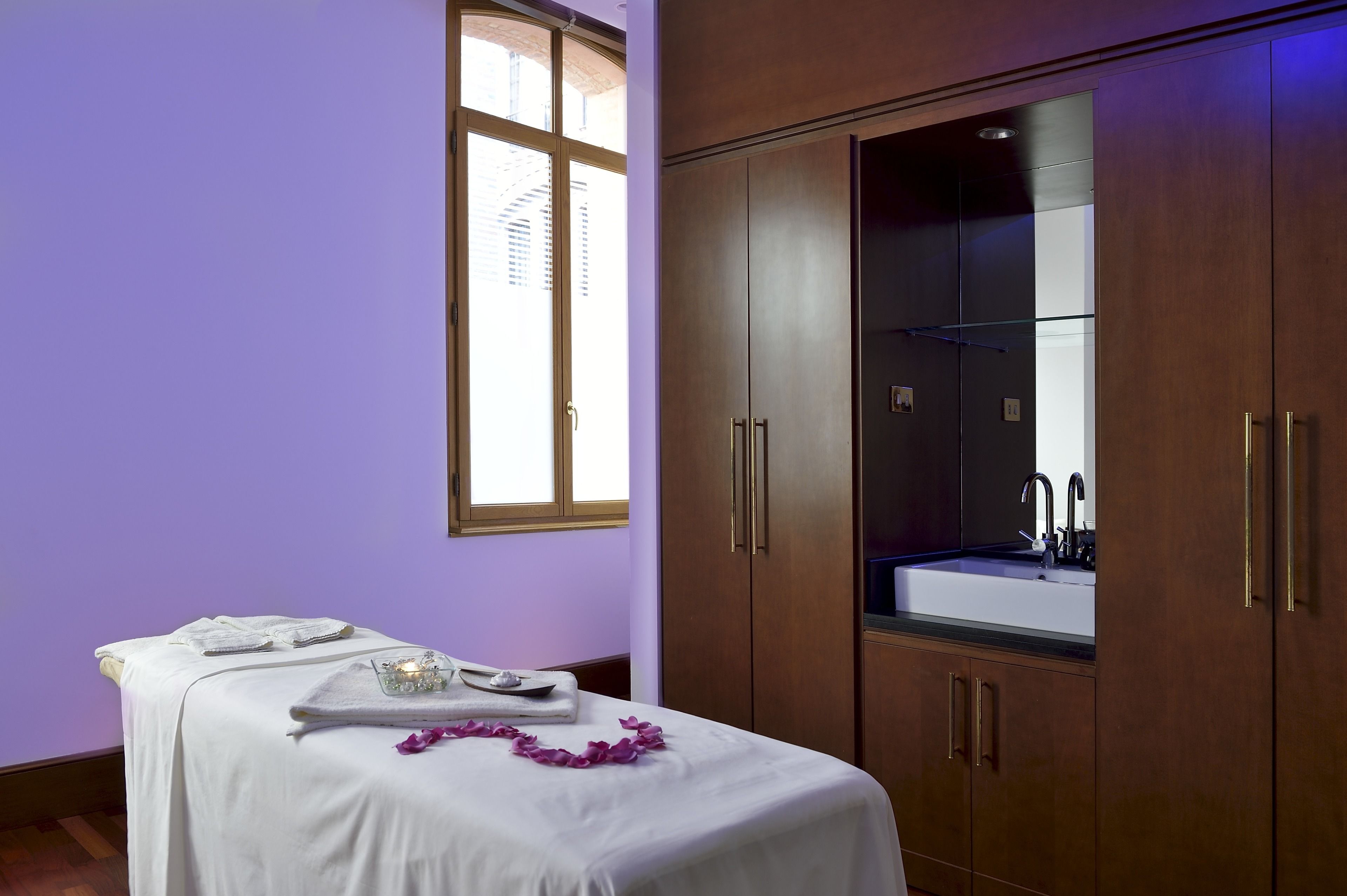 A room with a bed, a large wardrobe, a sink, and a window.