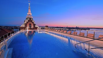 A swimming pool with a view of a cityscape and a distinctive building with a spire.