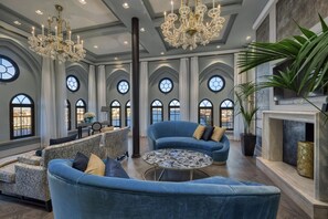 A spacious room with a grand chandelier, a fireplace, and a view of the city through large arched windows. - Hilton Molino Stucky Venice (Venice)