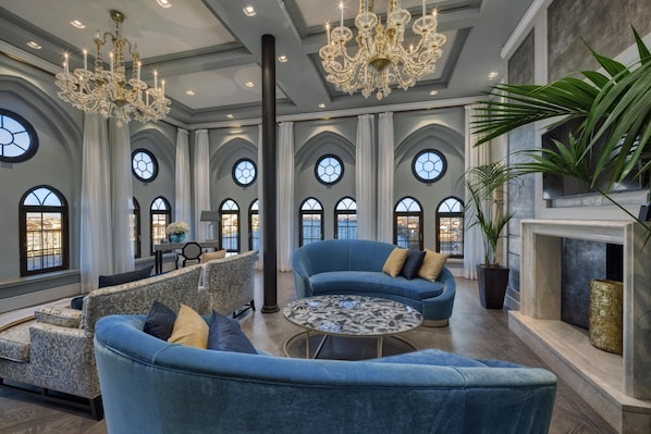 A spacious room with a grand chandelier, a fireplace, and a view of the city through large arched windows. - Hilton Molino Stucky Venice (Venice)