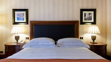 Un cuarto de hotel con una cama grande, dos mesitas de noche con lámparas, y cuadros enmarcados en las paredes.