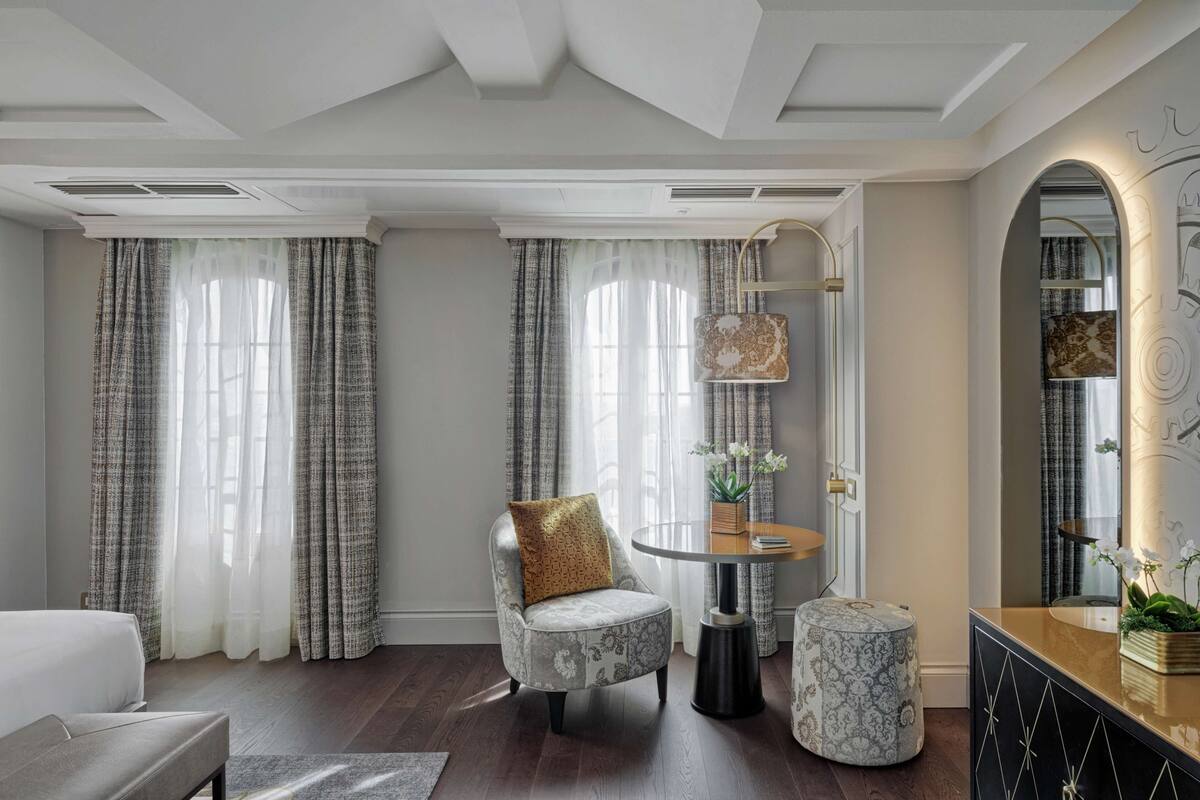 Un salon moderne avec un fauteuil à revêtement gris, une table d’appoint ronde et un pouf en marbre.