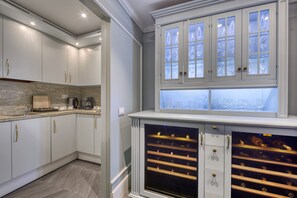 Cucina con pensili bianchi, un piano di lavoro in granito e una cantinetta per vini.