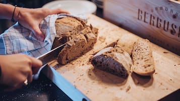 A person slicing a loaf of bread on a wooden cutting board.