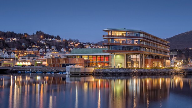 A multi-story hotel with a modern design, located near a body of water with reflections. - Quality Hotel Ulstein (Ulsteinvik)