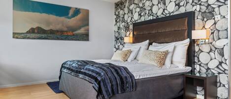 Una camera da letto con un letto, un muro in pietra, un quadro e un comodino.