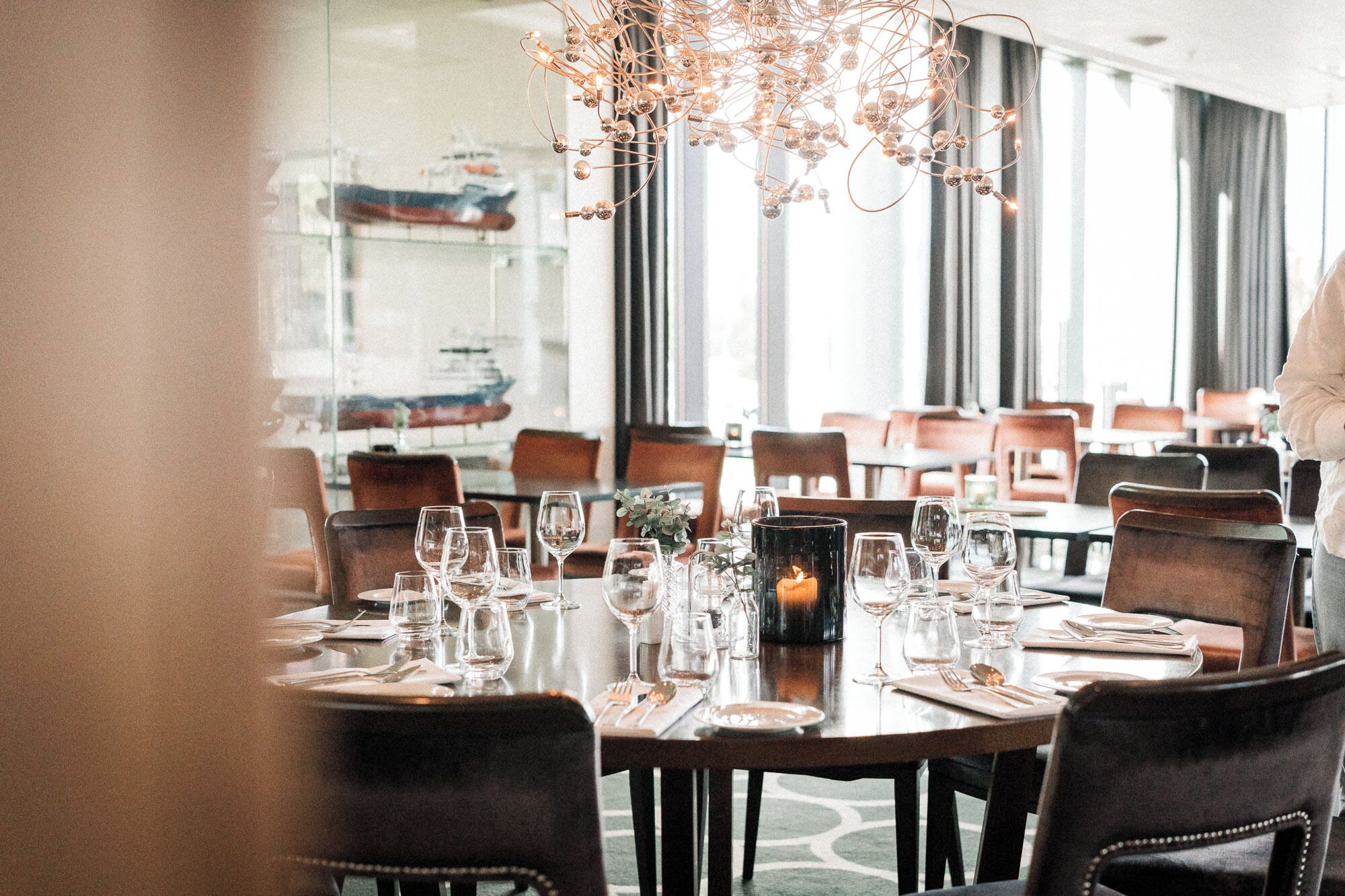 A dining area with a large round table set for a meal, surrounded by chairs.