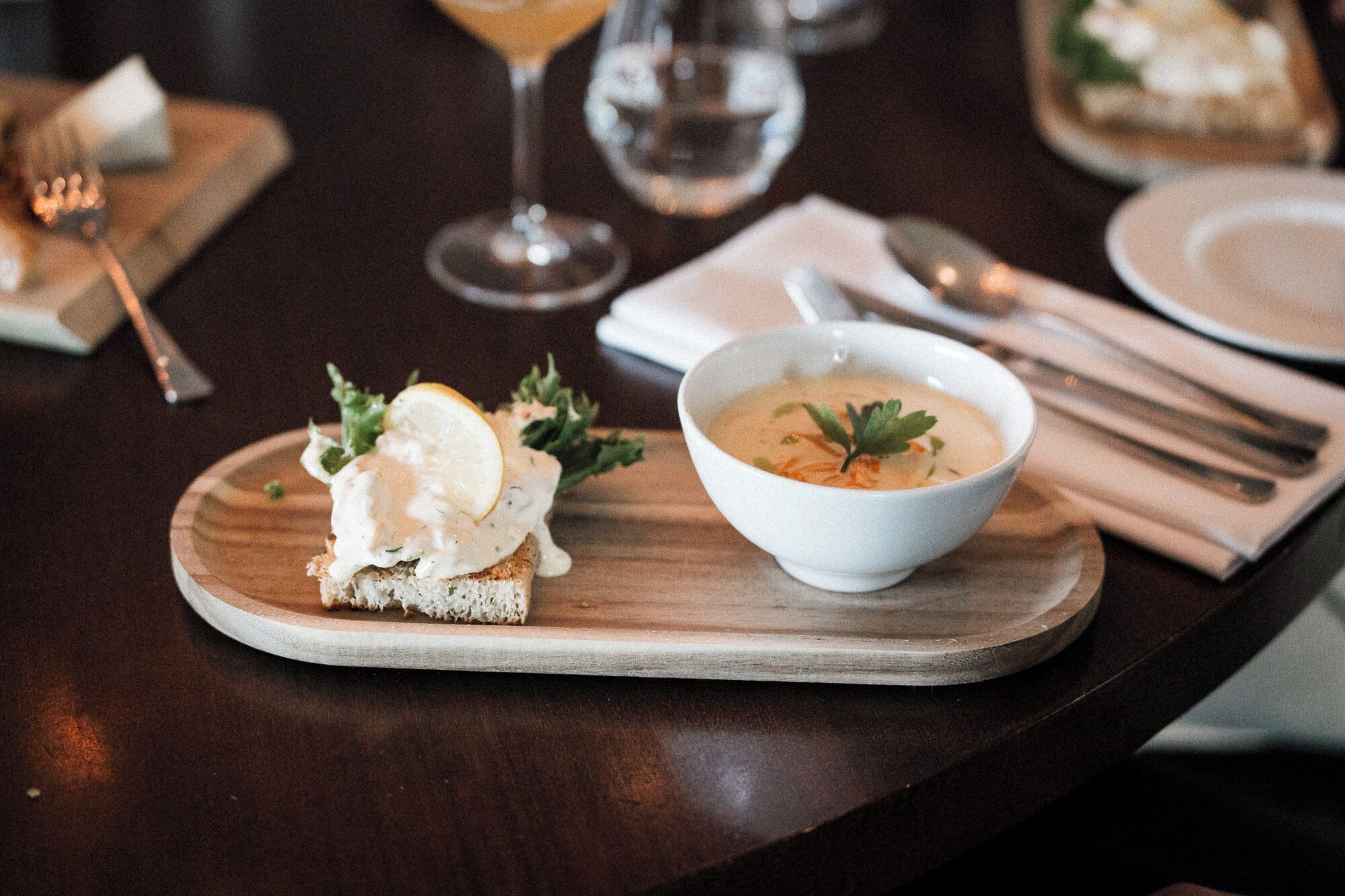 Une table à manger avec une assiette de nourriture, un bol de soupe et un verre de vin.