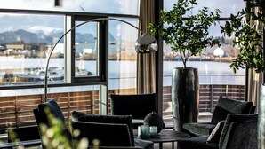 A modern lounge with a view of a marina, featuring dark-toned furniture and a large potted plant. - Quality Hotel Ulstein (Ulsteinvik)