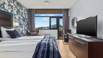 Una habitación de hotel moderna con una cama grande, un televisor, un cabecero de madera y una pared de piedra.