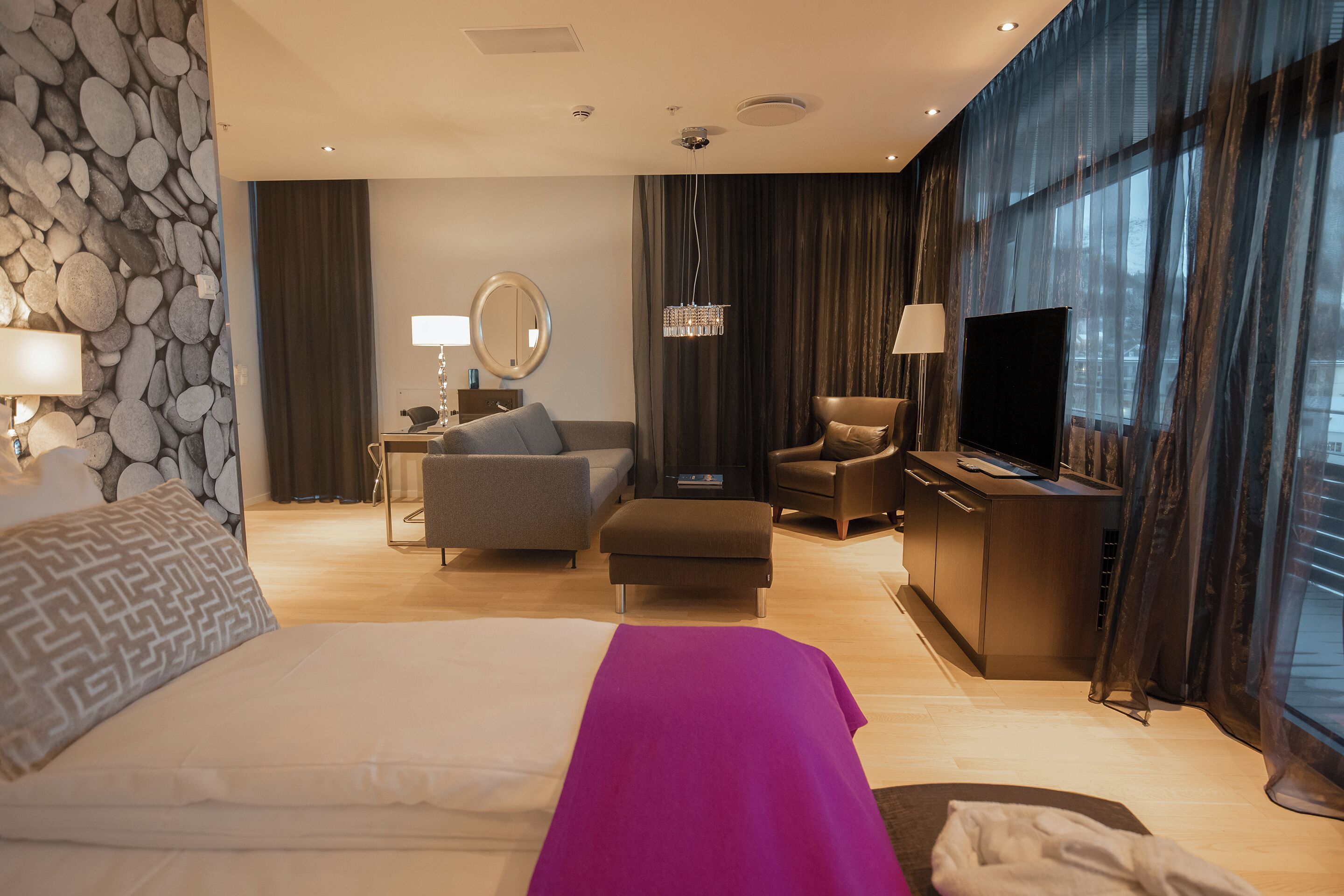 Una habitación de hotel con cama, escritorio, televisión y zona de estar.