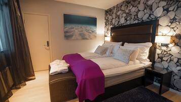 Ein Schlafzimmer mit Bett, Nachttisch, Bank, einer Wand mit Steinmuster und einem Strandbild.