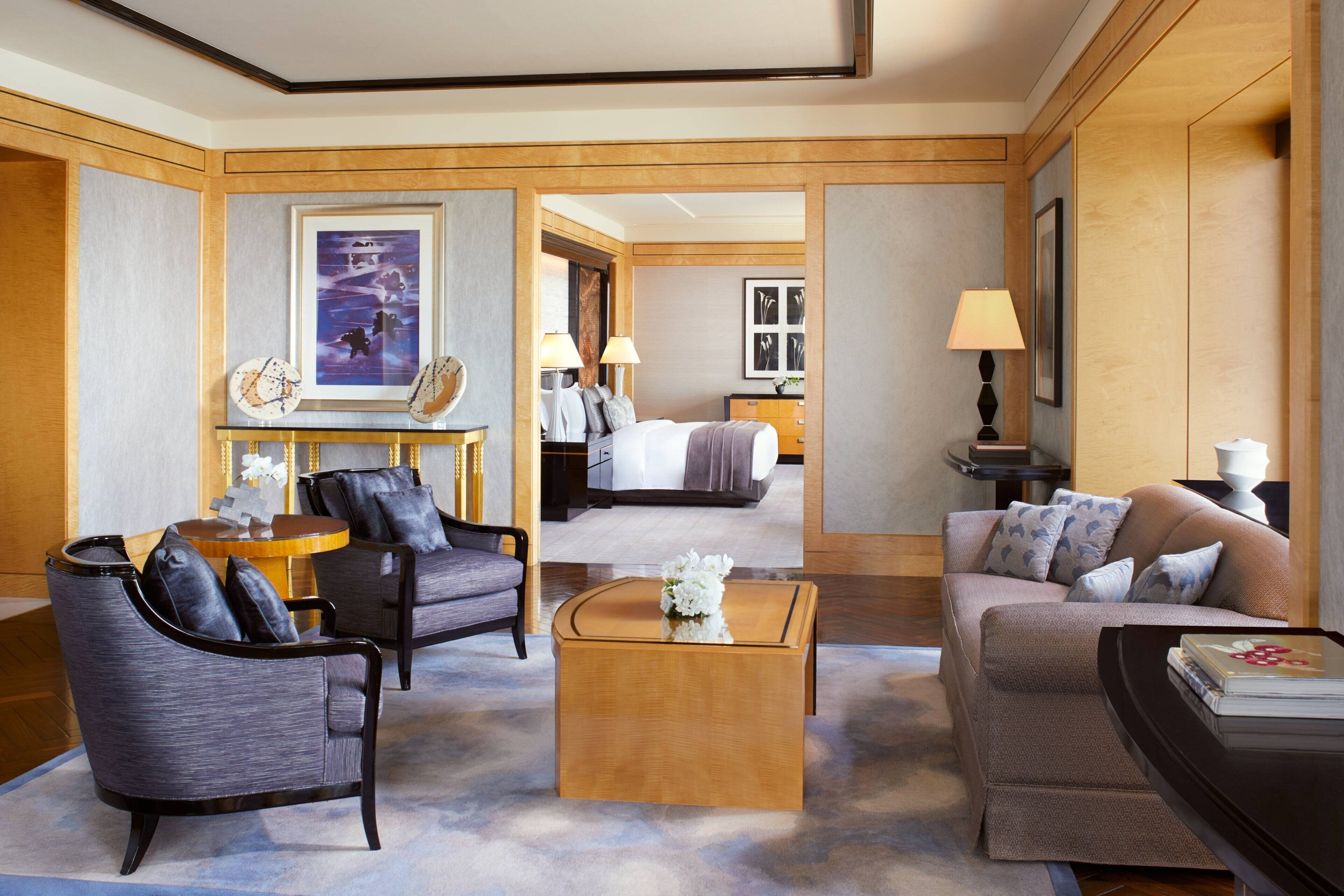 A hotel room with a bed, two armchairs, a sofa, a coffee table, and a side table with a lamp.