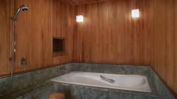 A wooden-paneled bathroom with a freestanding bathtub, a showerhead, and a small wooden stool.