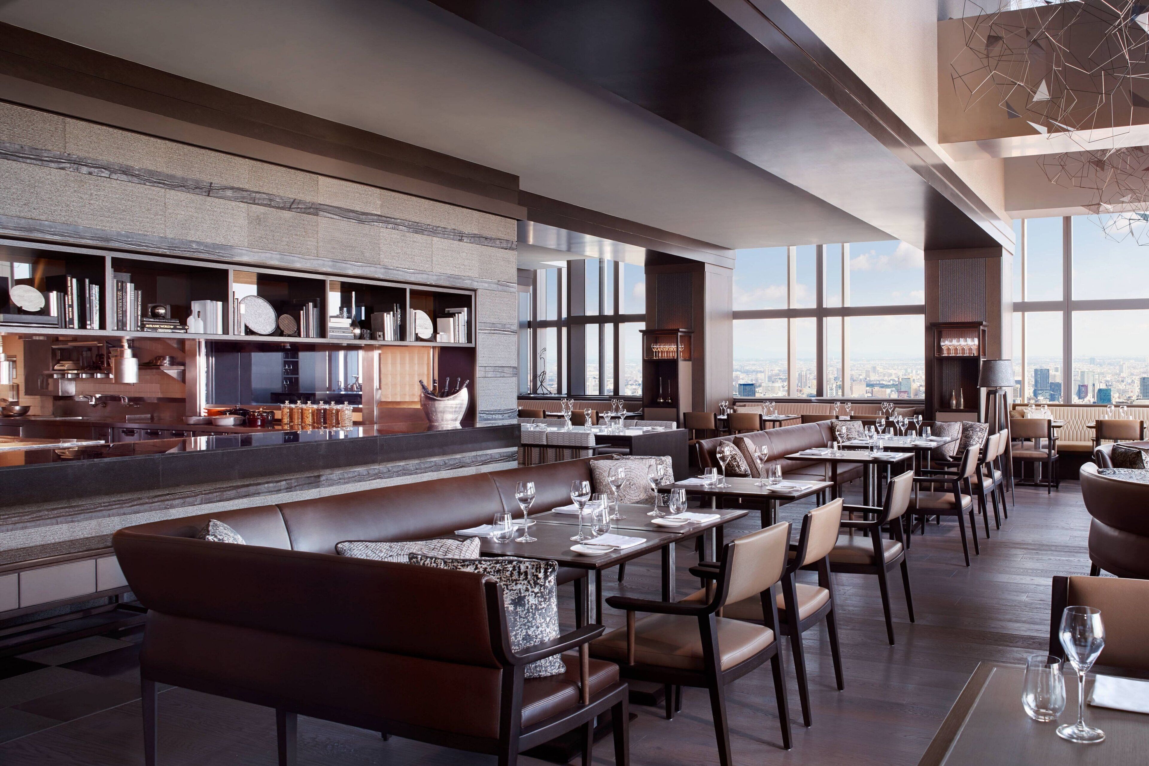 A modern restaurant with high ceilings, large windows, and a city view.