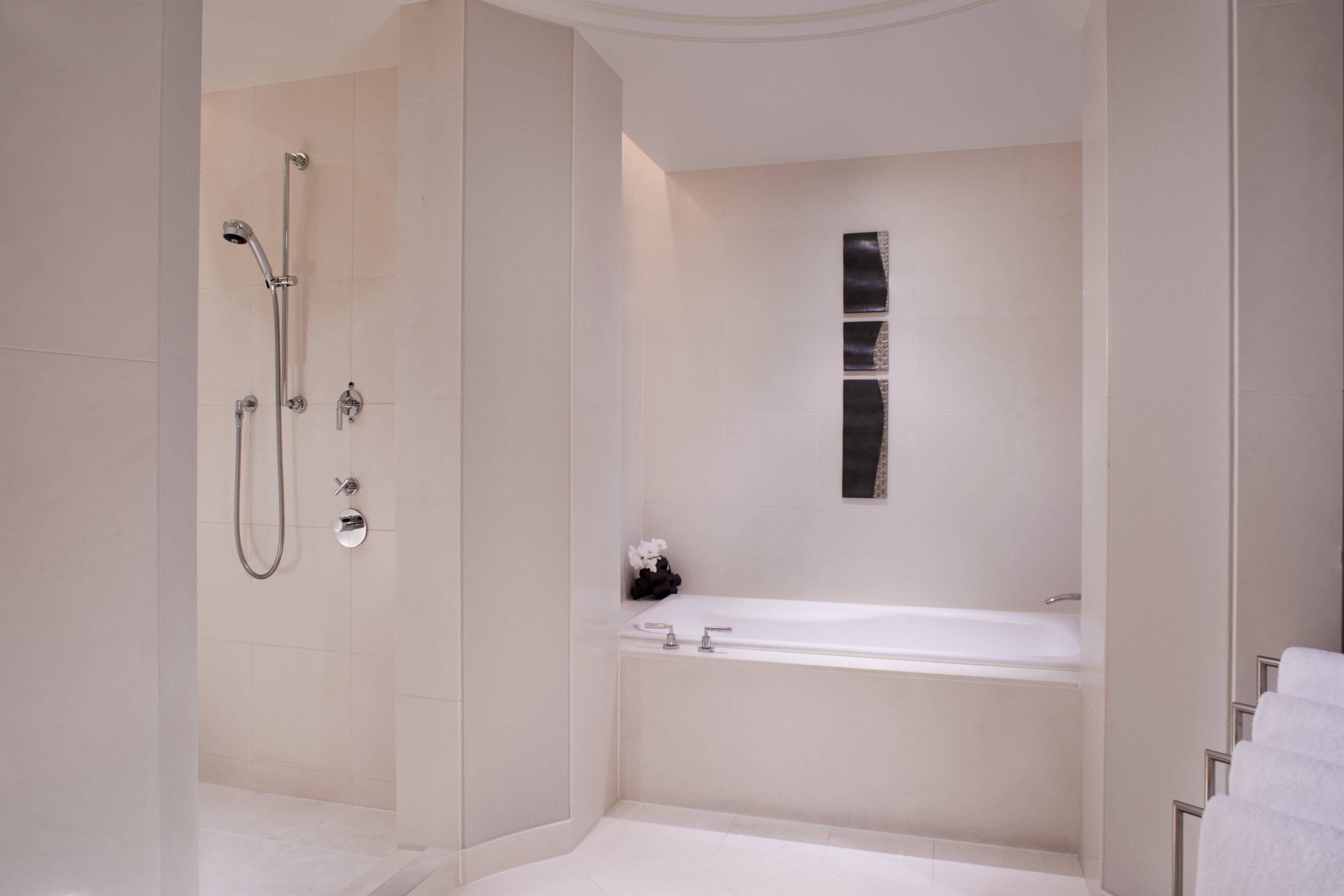 Un baño moderno con ducha a ras de suelo, bañera independiente y lavamanos de pared.