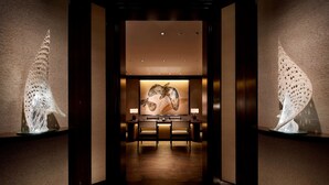 A hallway with a reception desk, two chairs, and a wall-mounted sculpture.