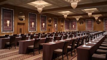 A conference room with long tables, chairs, and chandeliers.