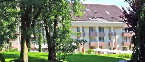 Un hôtel à plusieurs étages, doté d’un toit plat, de balcons et d’une pelouse bien entretenue.