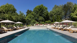 A rectangular swimming pool with lounge chairs and umbrellas along the sides. - Residence La Reserve (Ferney-Voltaire)