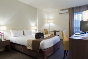 Una habitación de hotel con cama, mesitas de noche, escritorio, silla y televisor.