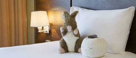 A neatly made bed with a plush toy and a decorative pillow.